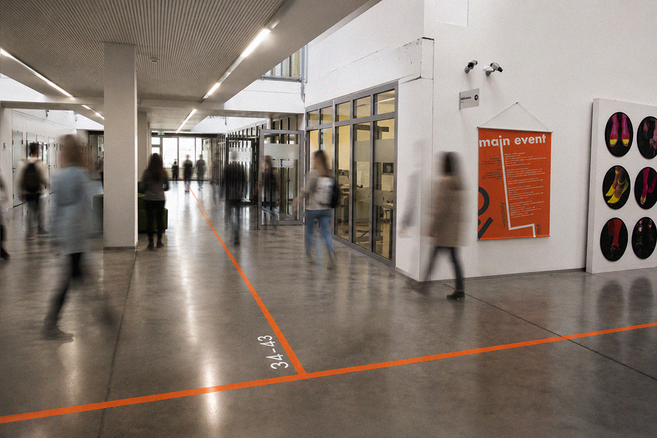 Orange wayfinding line installed across a university corridor